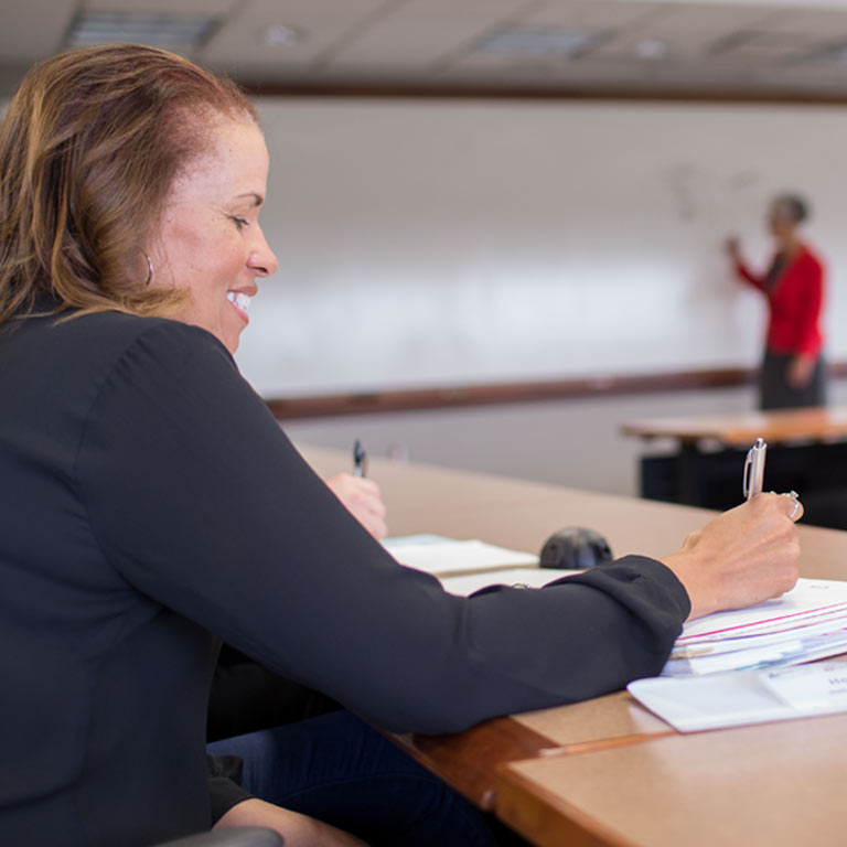 A woman takes notes during an executive education class.