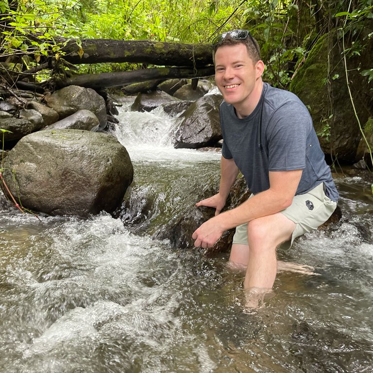 Student kneeling in a river.