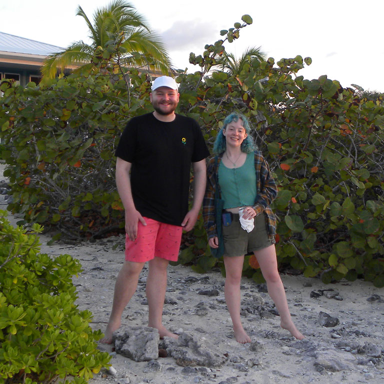 Two students posing for a photo on a beach.